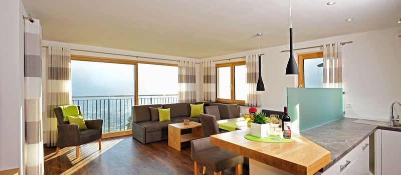 Soggiorno moderno con divano grigio, poltrone, tavolo da pranzo e cucina con bancone