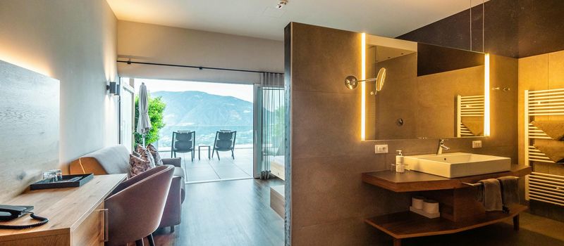 Interno di una stanza d'hotel moderna con bagno e vista sulle montagne da un balcone