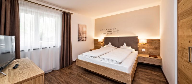 Camera da letto moderna con letto matrimoniale, pareti bianche e pavimento in legno.