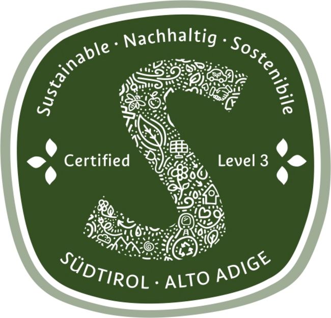 Grünes Siegel mit weißem, dekorativ gemustertem S und den Aufschriften „Sustainable · Nachhaltig · Sostenibile“, „Certified“, „Level 3“ und „Südtirol · Alto Adige“.