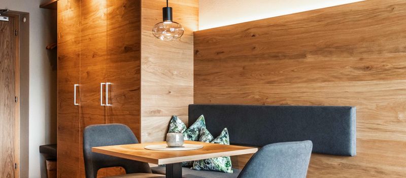 Sala da pranzo moderna con tavolo in legno, sedie grigie e pareti con rivestimento in legno.