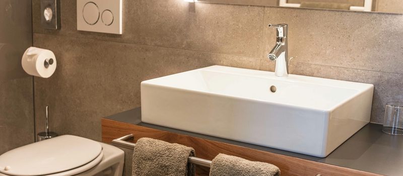 Bagno moderno con lavabo rettangolare, asciugamani e WC.